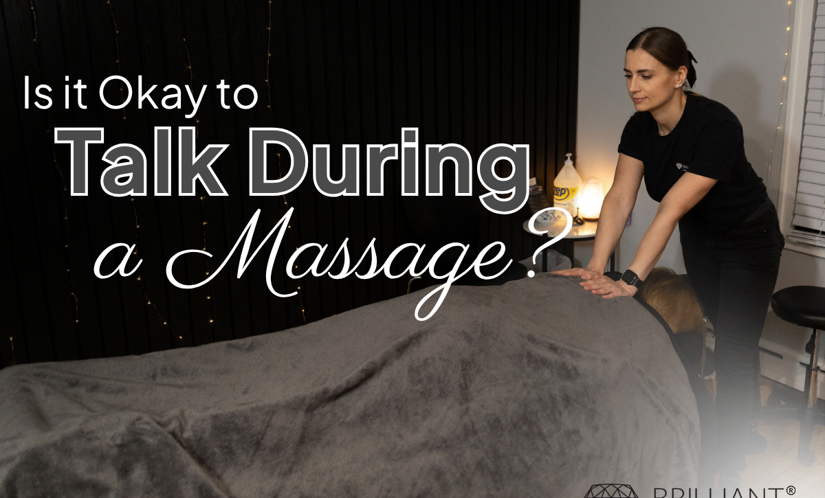 A therapist giving an upper back massage a client lying on a massage table covered by a brown sheet. Text saying "Is it Okay to Talk During a Massage?"